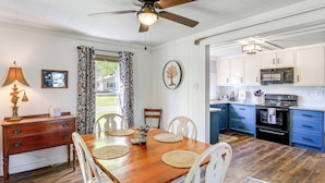 A dining area with a wooden table, white chairs, and a ceiling fan. - Walk to River & Trails: Cozy Damascus Cottage! (Damascus)