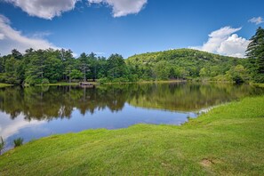 Un lac paisible, bordé d’une végétation luxuriante, sous un ciel bleu et dégagé.