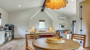 Un dormitorio estilo loft acogedor con techo inclinado, una cama con cabecera y un ventanal con persianas.