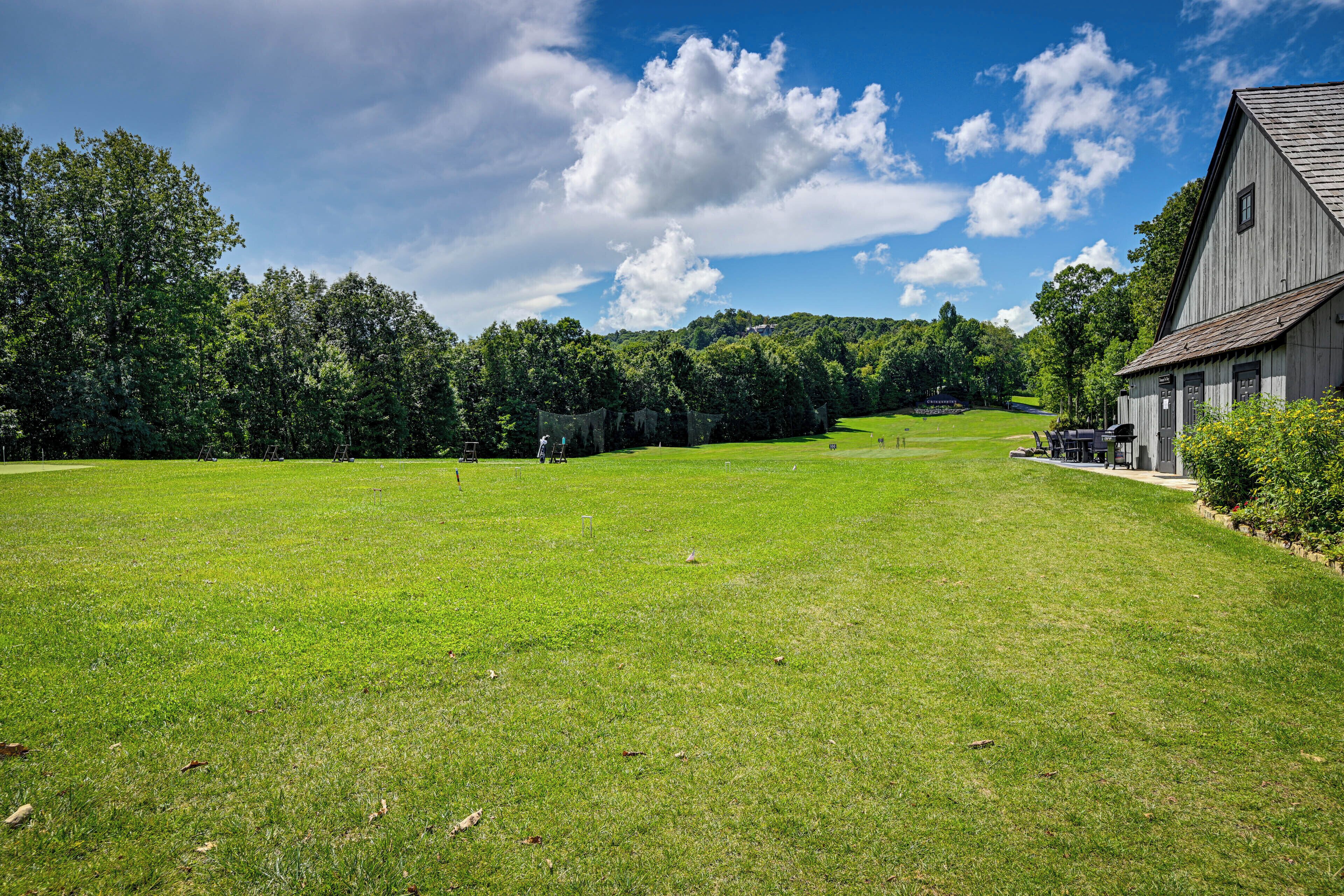 A large grassy field with a barn and trees in the background.