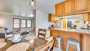 Een moderne keuken met houten kastjes, een centraal eiland, barstoelen en een eettafel gedekt met placemats.