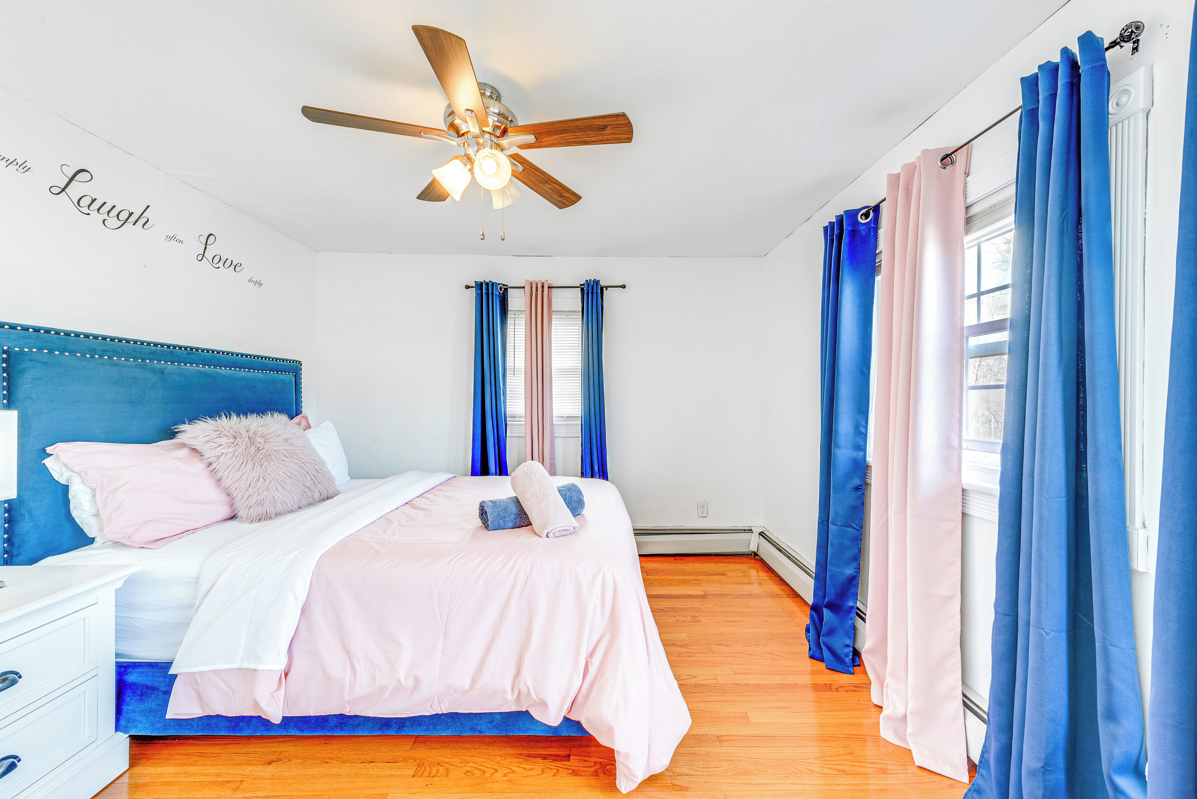 Un dormitorio con cama, ventilador de techo y cortinas.