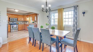 A kitchen with wooden cabinets, a microwave, and a dining area with a table and chairs. - Poconos Group Getaway w/ Game Room + Fire Pit! (Gouldsboro)