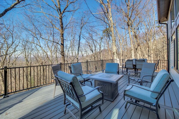 Une terrasse dotée de mobilier d’extérieur, notamment de chaises et d’une table, qui offre une vue sur une zone boisée.