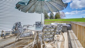 An outdoor patio with a round table, four chairs, and a large umbrella. - Algoma Lake Michigan Home w/ Game Room & Deck (Algoma)
