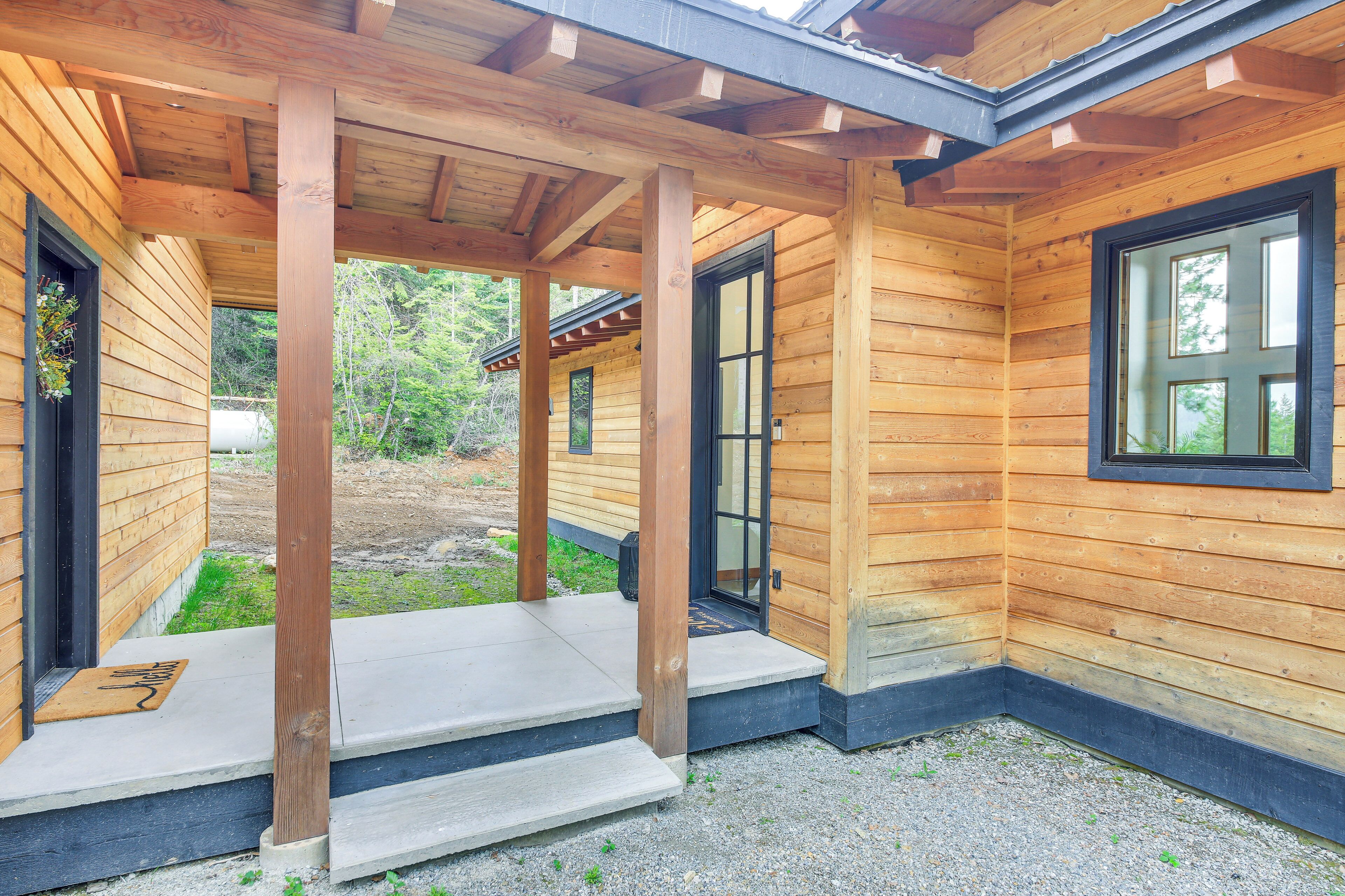 A wooden cabin with a covered porch, a door leading to the interior, and a small outdoor area with steps.