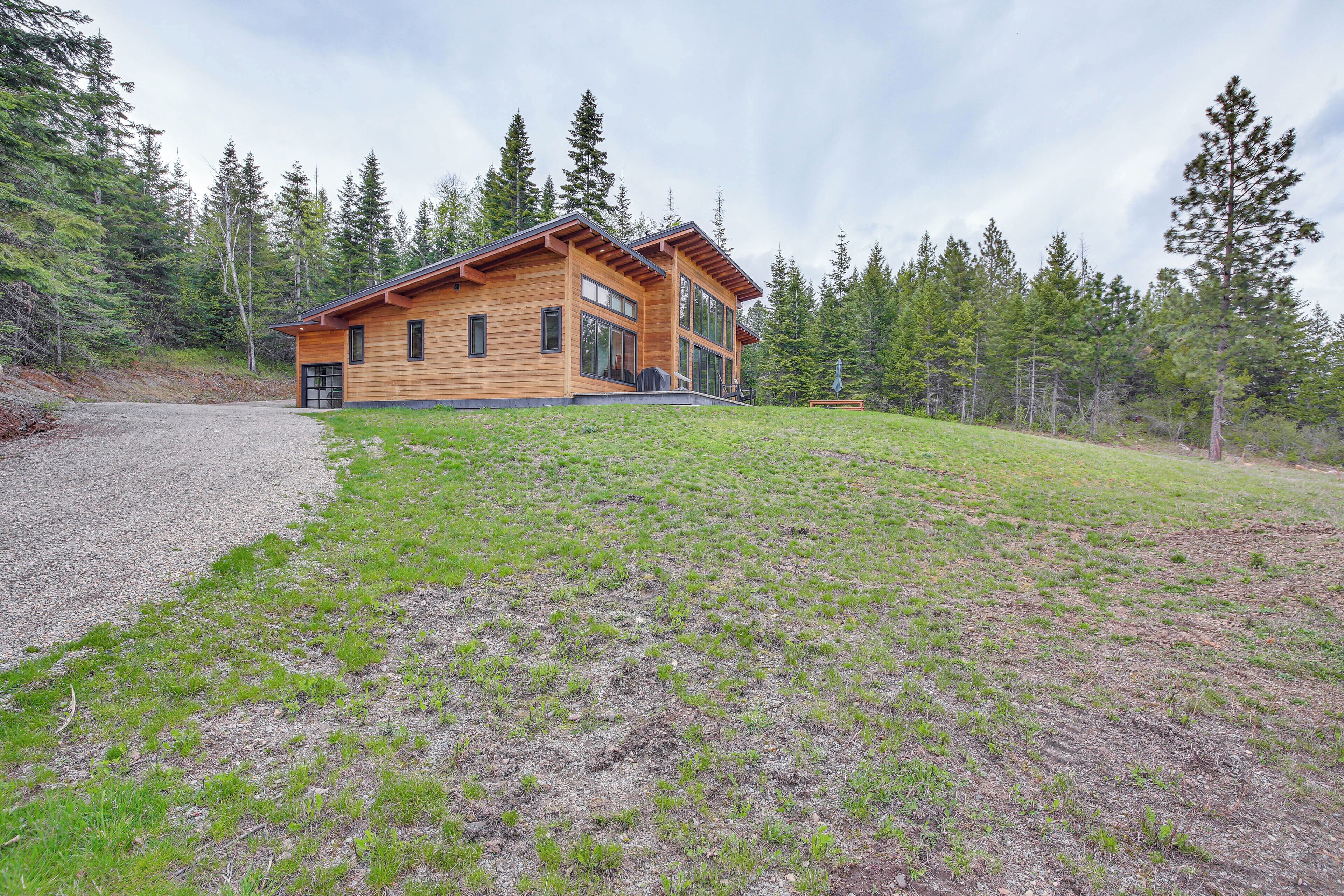 Une cabane en bois dotée de grandes fenêtres et d’une allée gravillonnée.