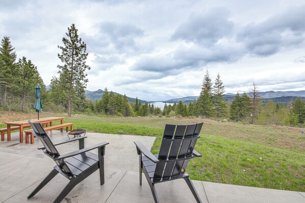 An outdoor patio with two Adirondack chairs, a wooden table, and a bench. - Luxe Mtn-view Escape 5 Mi to Dtwn Priest River! (Priest River)