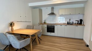 Une cuisine moderne avec des armoires blanches, un plan de travail en bois et un four encastré.