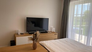 A hotel room with a bed, a wooden dresser, a television, and a window with curtains. - Mountain idyll -renovated and high quality with solid wood bed at comfort height (Altenberg)