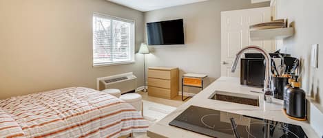 A modern bedroom with a bed, bedside table, and a desk with a sink.