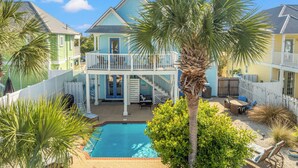 A two-story house with a balcony, a swimming pool, and a fenced patio area.