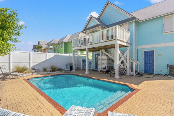 A pool area with a rectangular pool, a covered deck with a railing, and a white fence. - Seafoam Beautiful 3BR Home With Heated Private Pool - 4 Min Walk to Beach! (Panama City Beach)