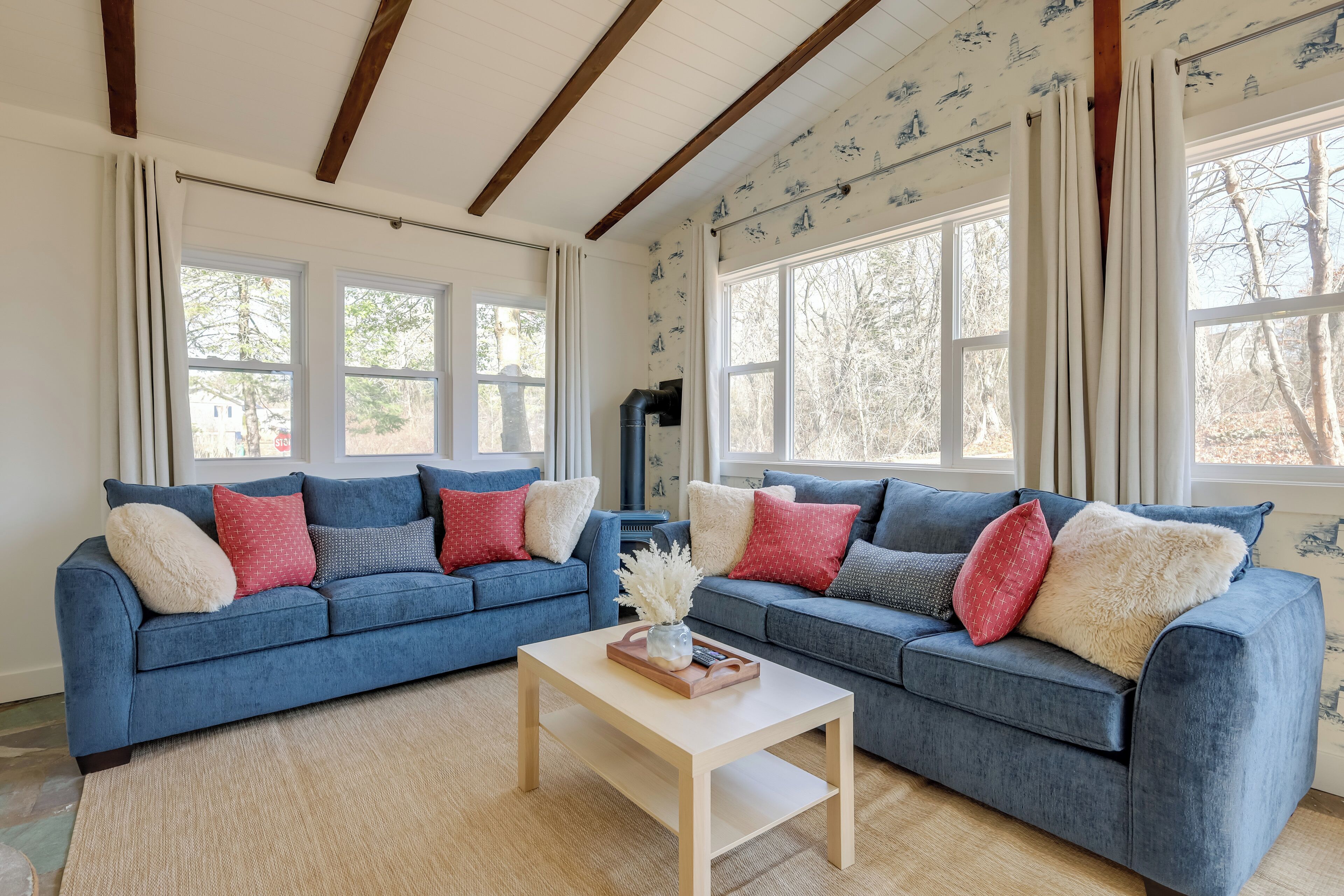 Un salon avec deux canapés bleus, une table basse en bois et de grandes fenêtres avec des rideaux.