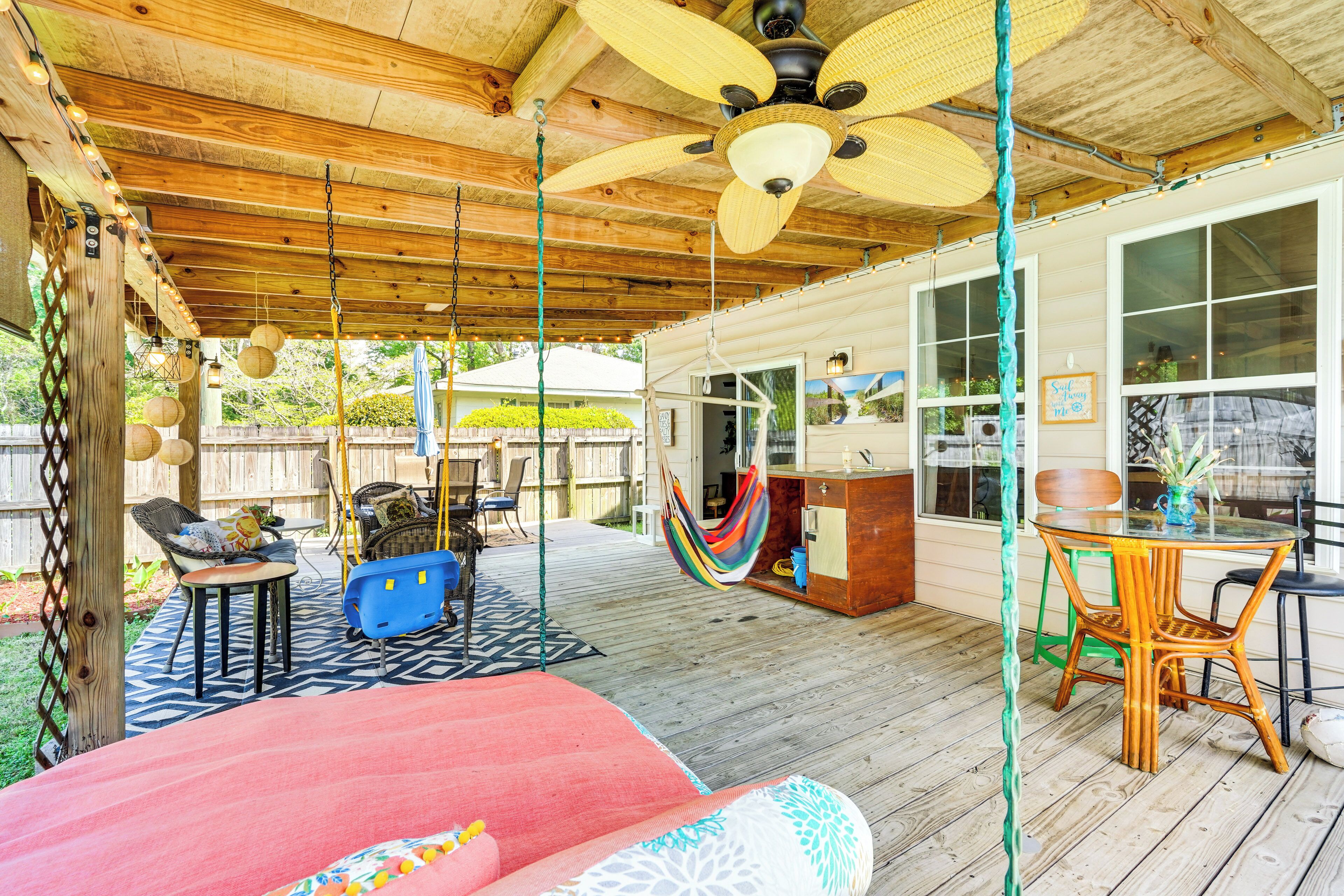 Een overdekt terras met houten plafond, plafondventilatoren, een hangmat en een bar.