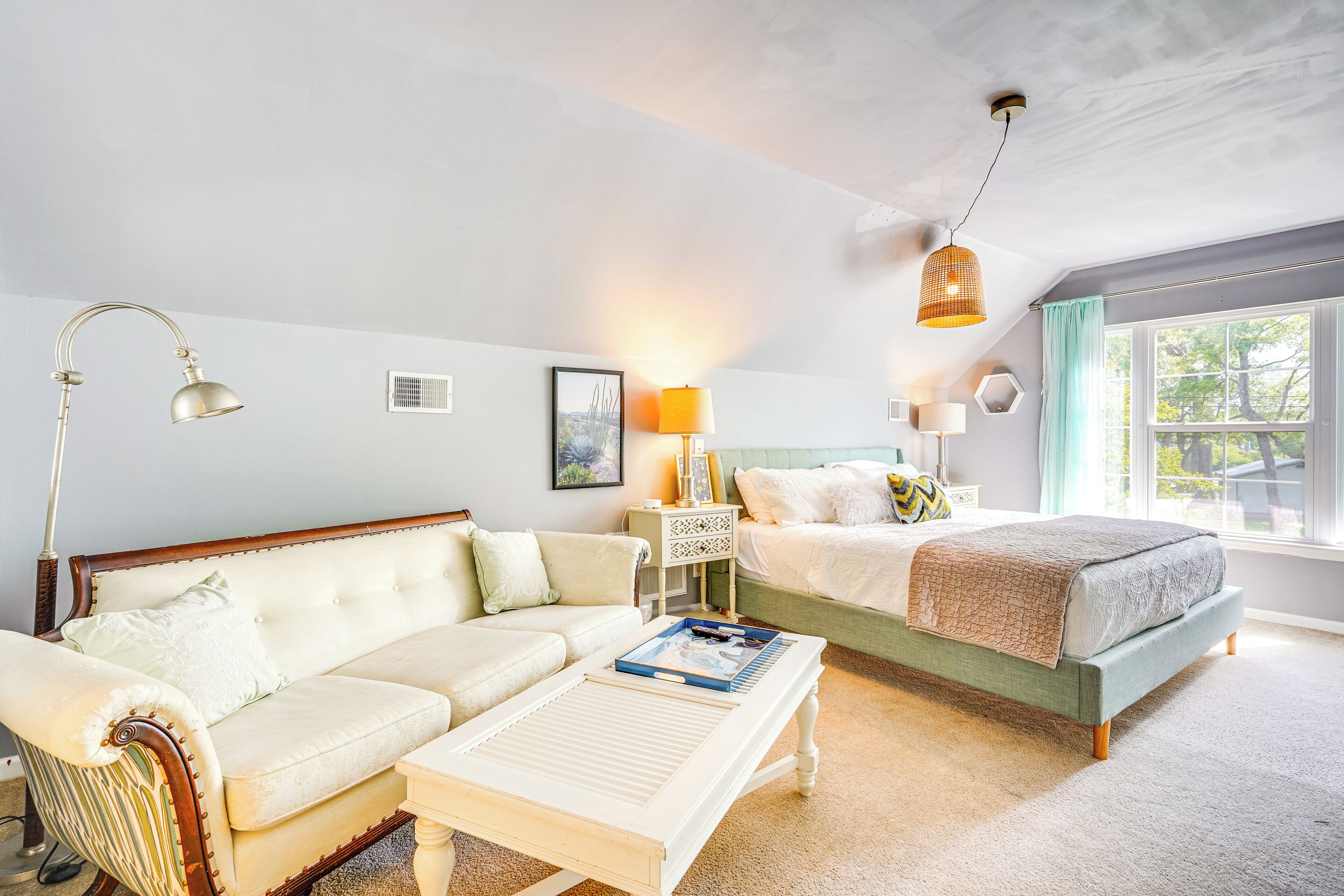 Un dormitorio con cama, sofá, mesita de noche y lámpara.
