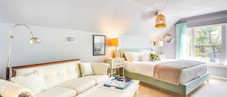 Un dormitorio con cama, sofá, mesita de noche y lámpara.