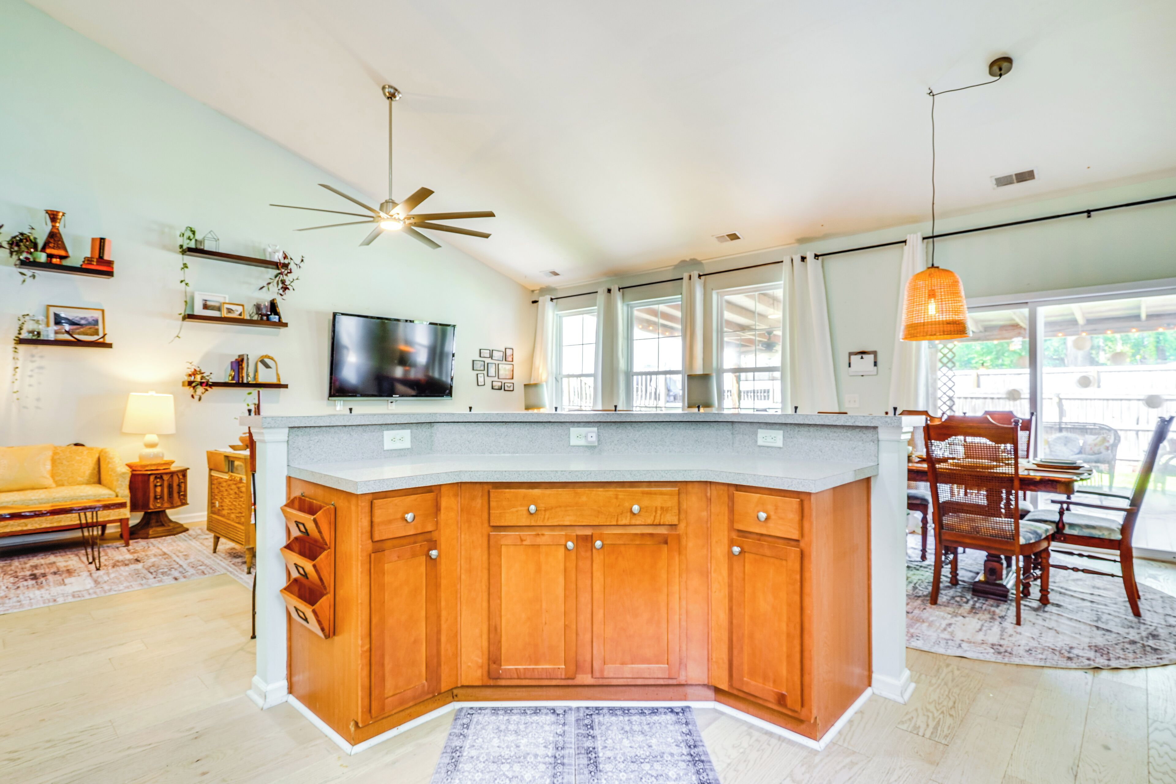 A modern kitchen with wooden cabinets, a central island, and a dining area with a table and chairs.