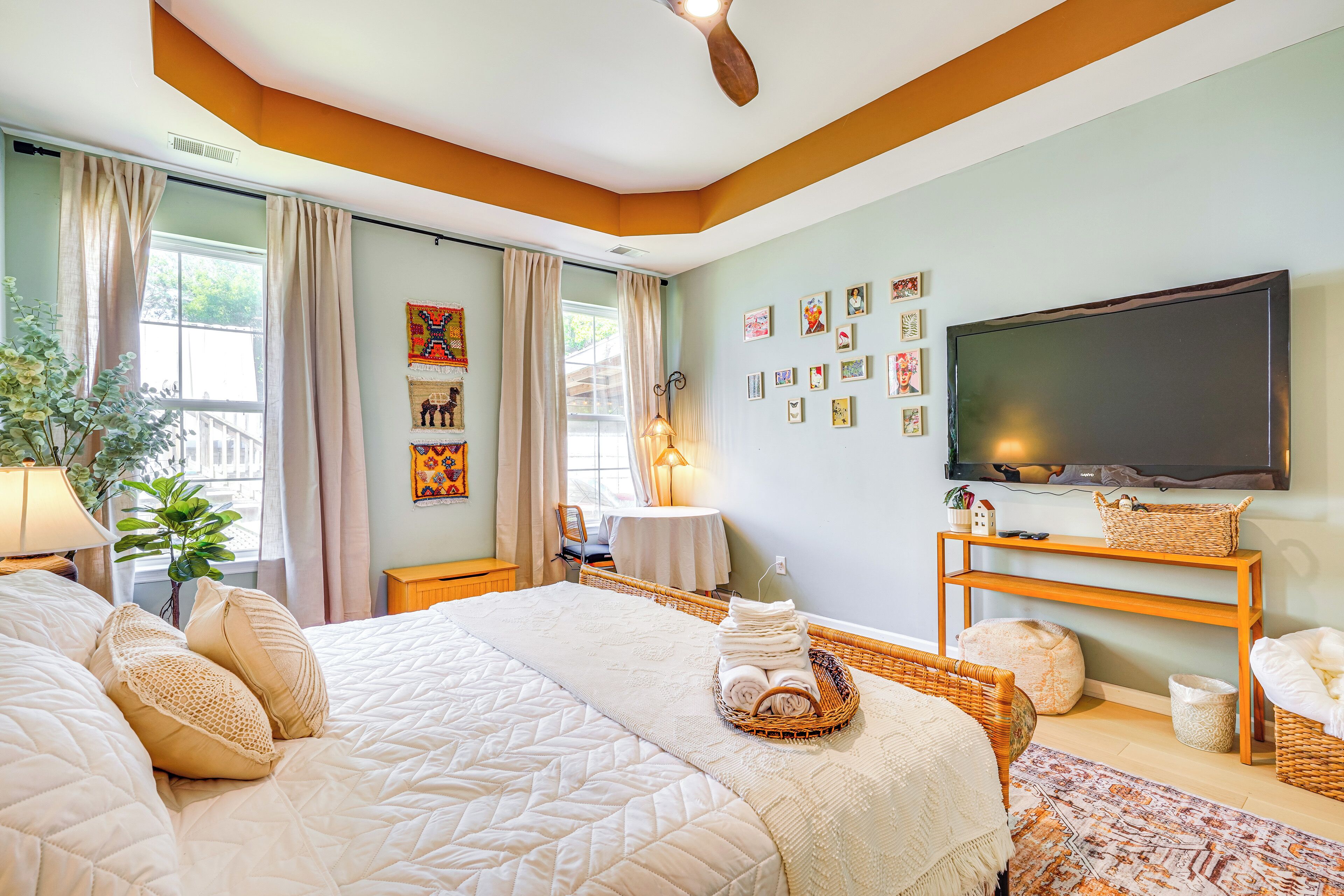 Een goed verlichte slaapkamer met een groot bed, een flatscreen televisie en diverse schilderijen aan de muur.