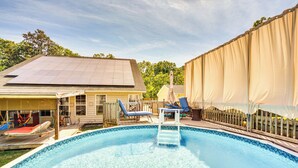Een zwembad met een trap, ligbedden en een overdekt terras.