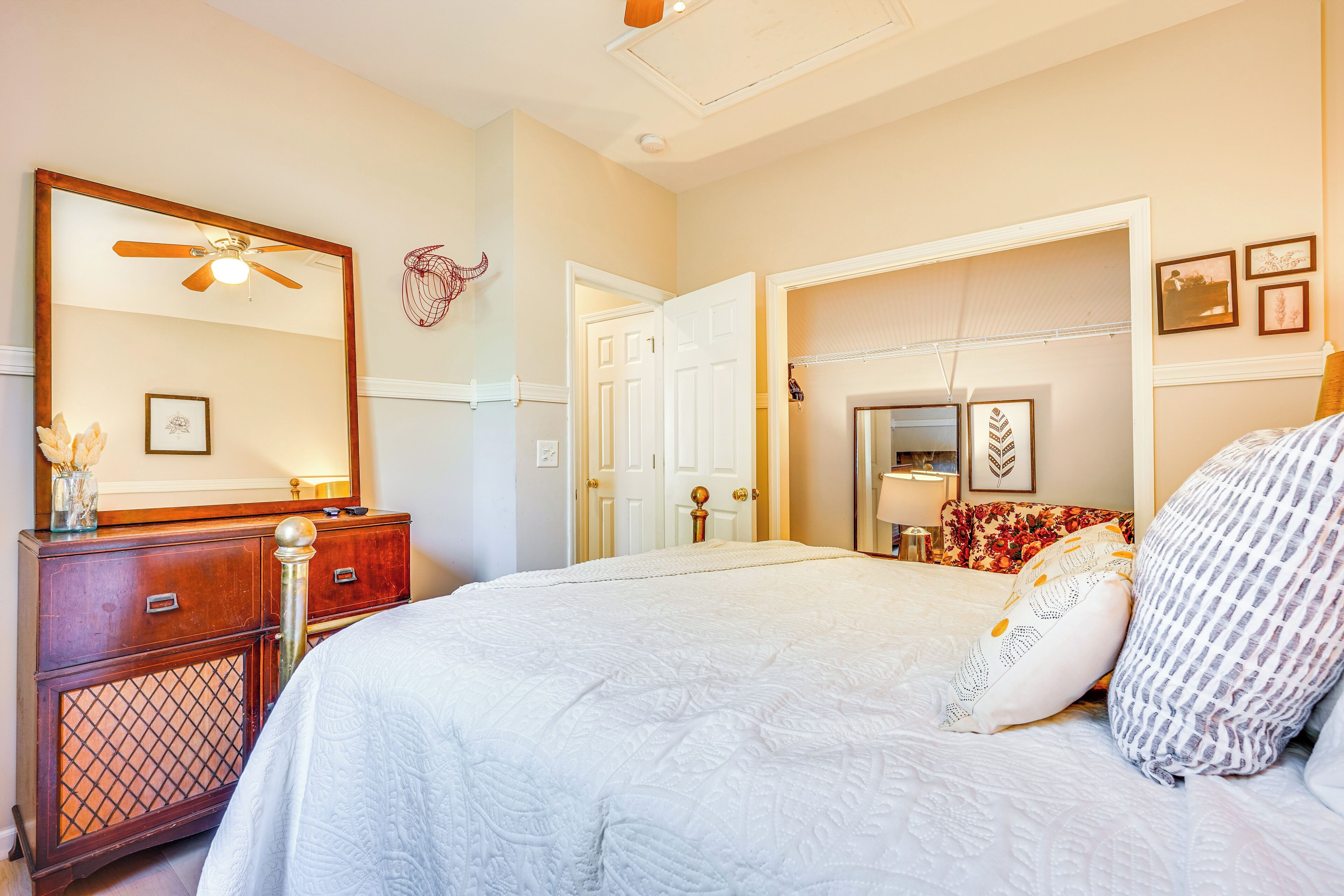 Un dormitorio con una cama grande, un aparador de madera, un ventilador de techo y un espejo.