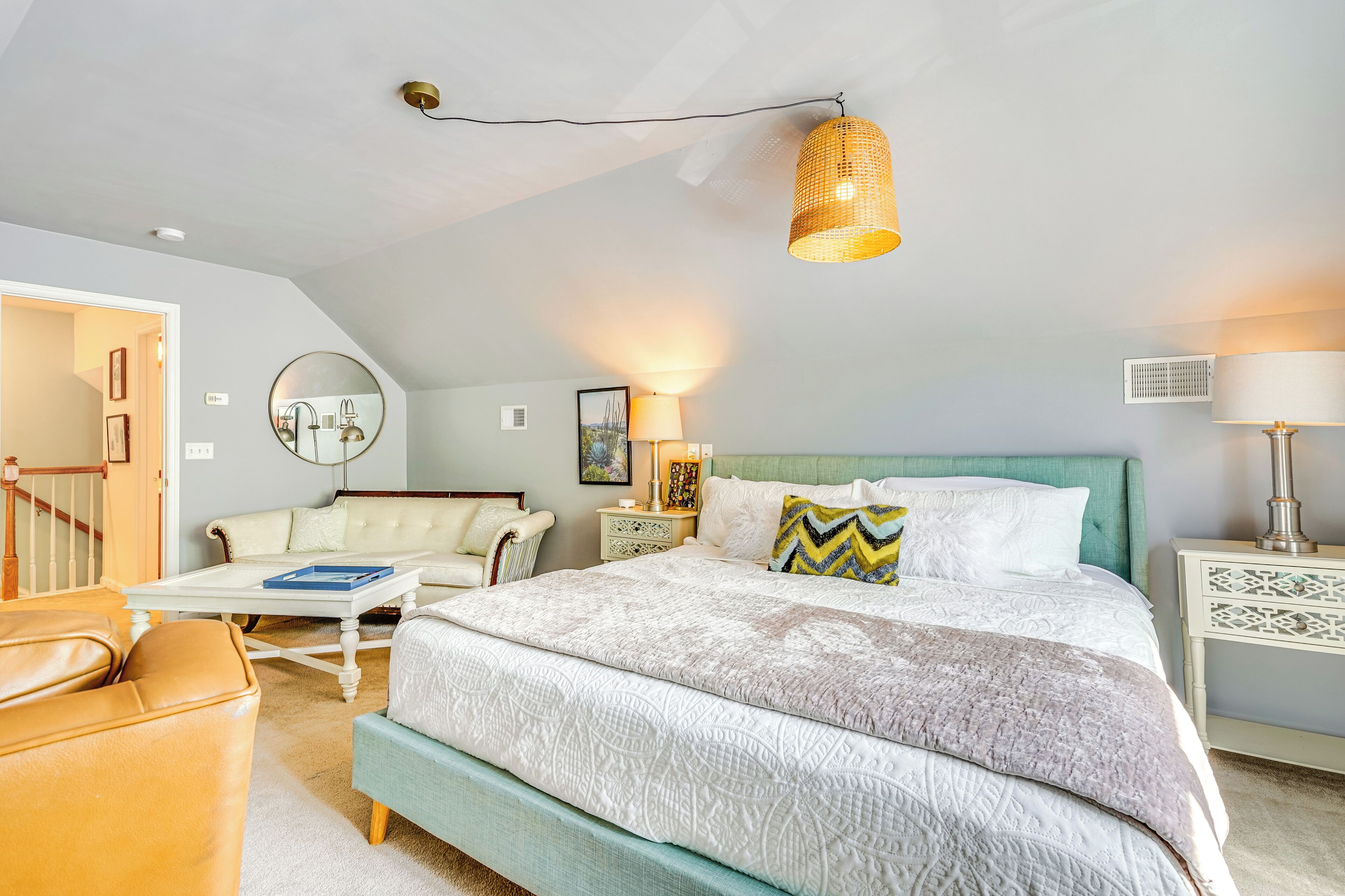 A bedroom with a large bed, a sofa, a coffee table, and a lamp.