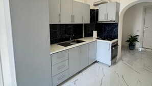 Una cocina moderna con gabinetes grises, un salpicadero de mármol negro y un suelo de mármol blanco.