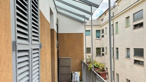 Un balcón con baranda de metal, una puerta y un felpudo.