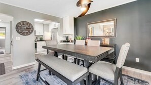 A dining area with a dark wooden table, grey upholstered chairs, and a modern pendant light.