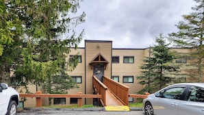 A building with a wooden staircase leading to a door, surrounded by trees.