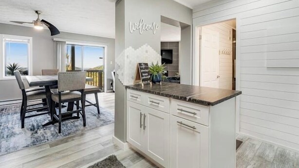 A modern kitchen with white cabinetry, a marble countertop, and a welcome sign on the wall.