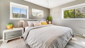A bedroom with a bed, bedside tables, a ceiling fan, and windows.