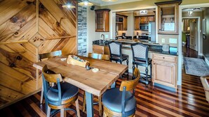 Une cuisine moderne avec des meubles en bois, un îlot central et un coin repas comprenant une table et des chaises en bois.