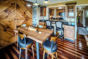 A modern kitchen with wooden cabinetry, a central island, and a dining area with a wooden table and chairs.