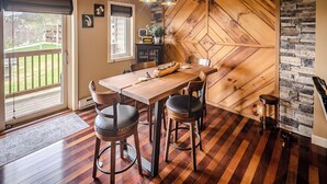 Un espace repas avec une table et des chaises en bois, un mur en pierre et une vue sur l’extérieur.