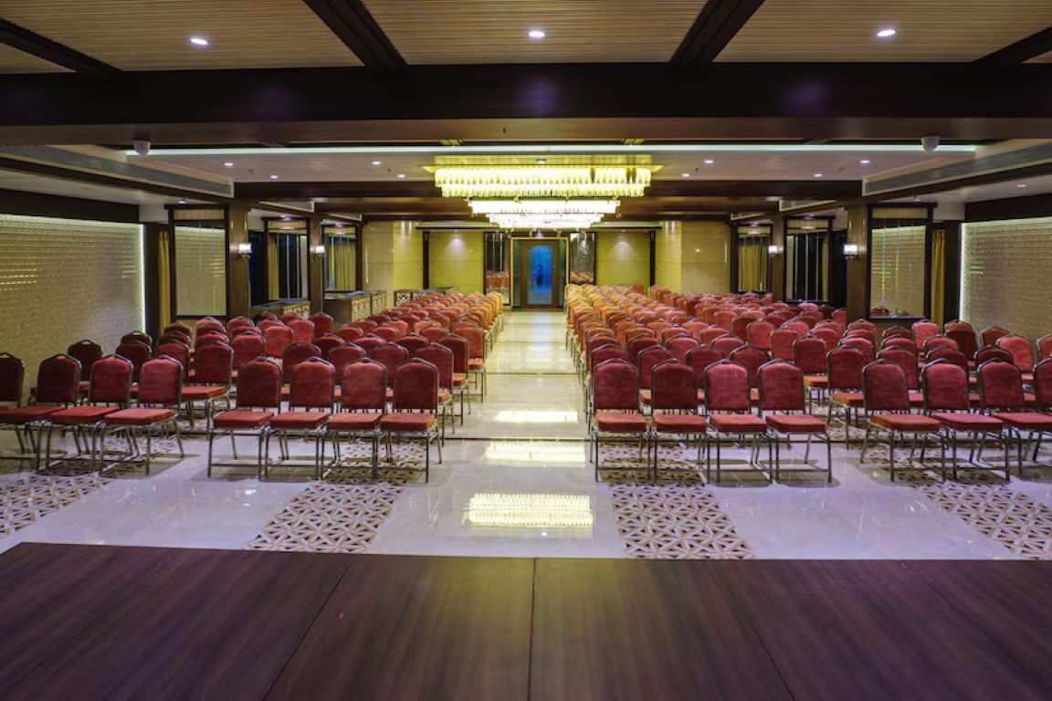 Un salón de conferencias con filas de sillas, una araña de cristal y un suelo pulido.