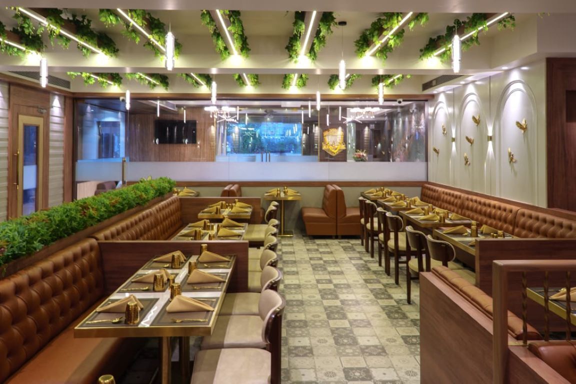 A restaurant with booth seating, a checkered floor, and green plants on the ceiling.