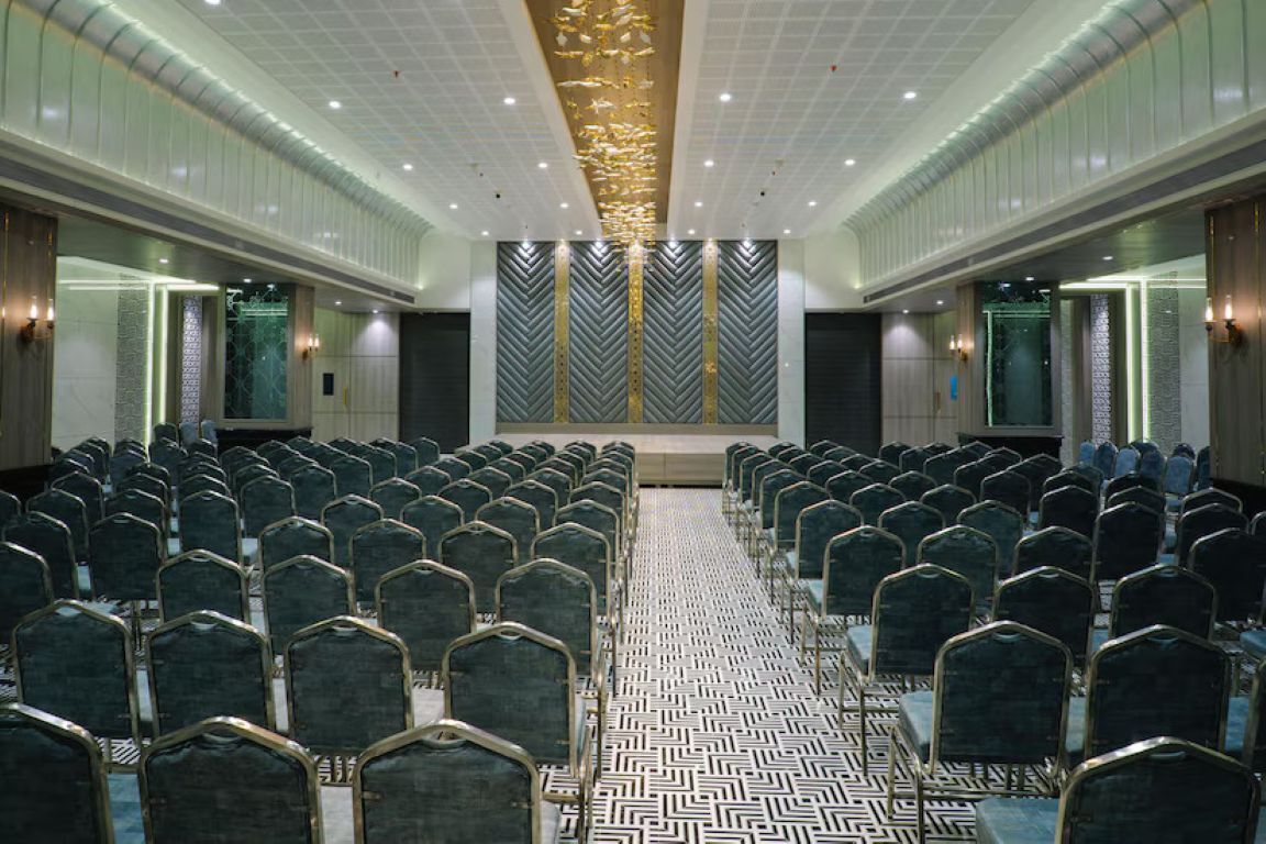 A conference room with rows of chairs, a patterned floor, and a decorative ceiling.