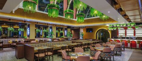 A spacious restaurant with high ceilings, hanging plants, and a variety of seating options including booths and tables.