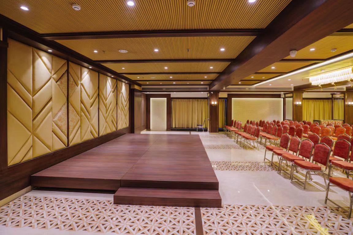 A conference room with a stage, rows of chairs, and patterned walls.