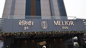 Een hoog hotelgebouw met een opvallend bord met de tekst 'MELIOR INN' en een bord in een andere taal.