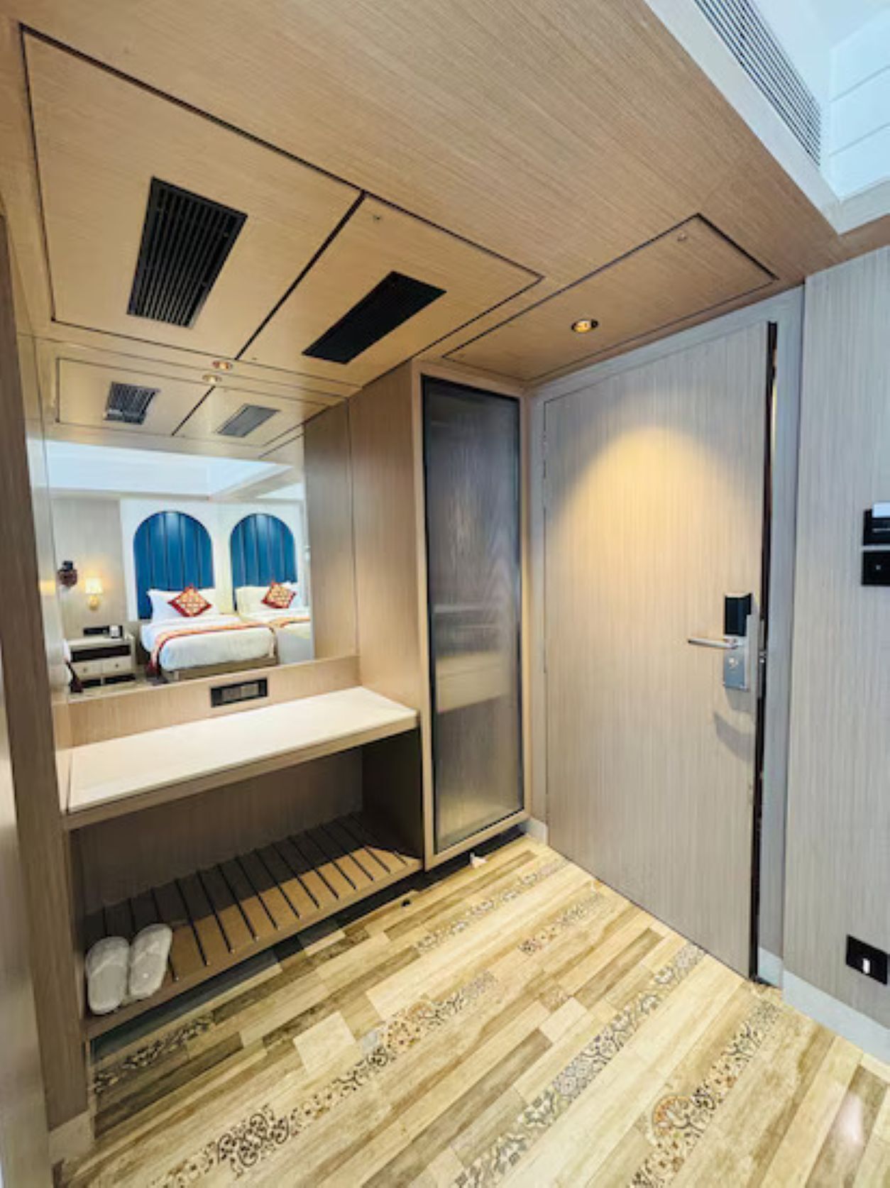 A hotel room with a bed, a desk, a wardrobe, and a mirror.