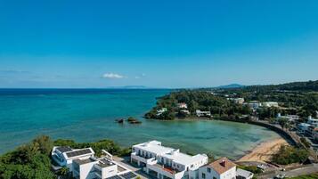 A coastal town with modern buildings, a beach, and clear blue waters.