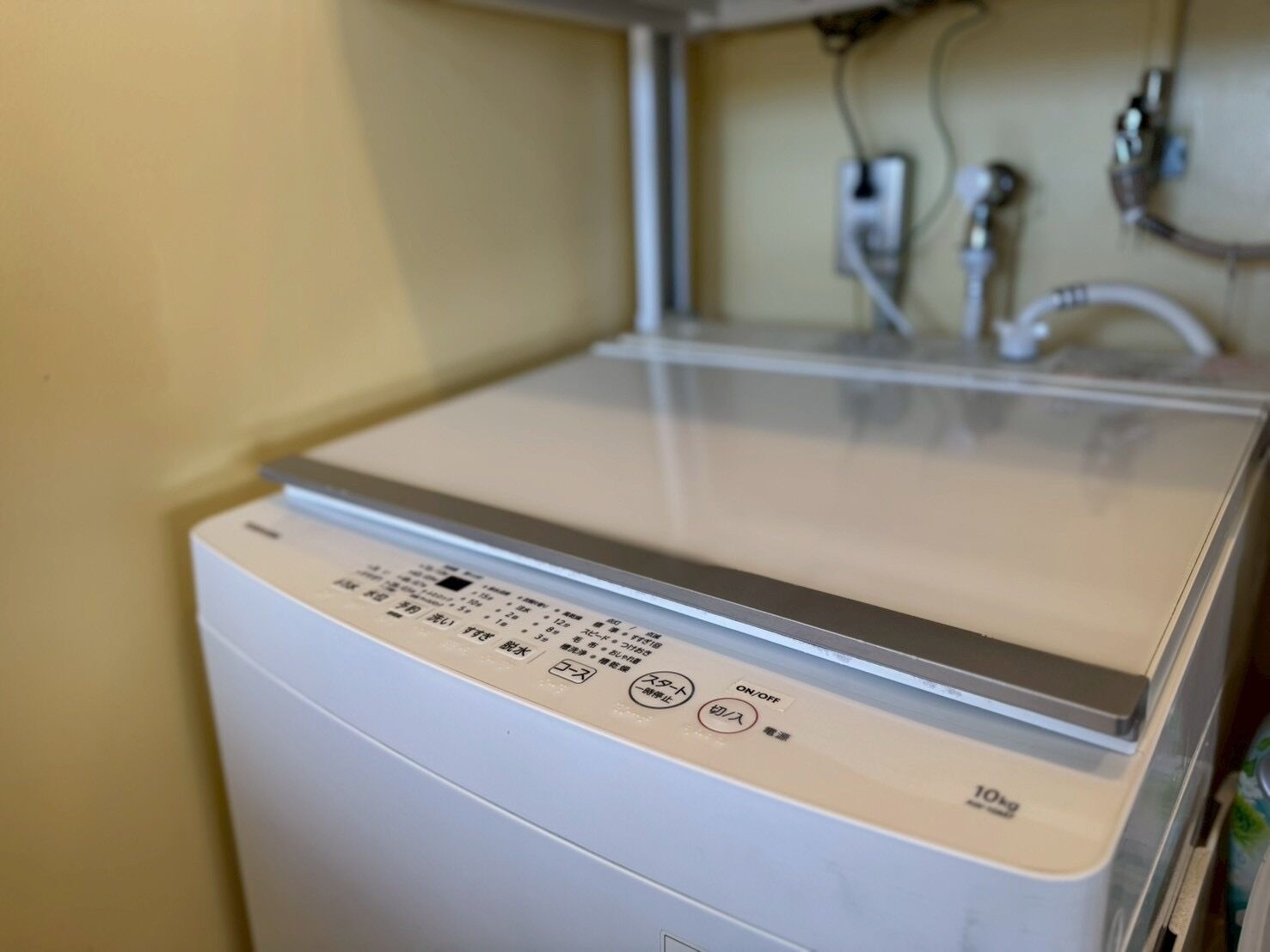 Eine weiße Waschmaschine mit Bedienfeld, Wasseranschluss und Ablaufschlauch.
