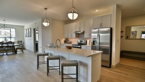 A modern kitchen with a central island, stainless steel appliances, and a dining area with wooden furniture. - Spacious condo centrally located in Silverthorne! (Silverthorne)