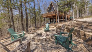 A cabin with a deck, surrounded by trees, and furnished with Adirondack chairs. - Timberline Lodge by Innsbrook Vacations! (Innsbrook)