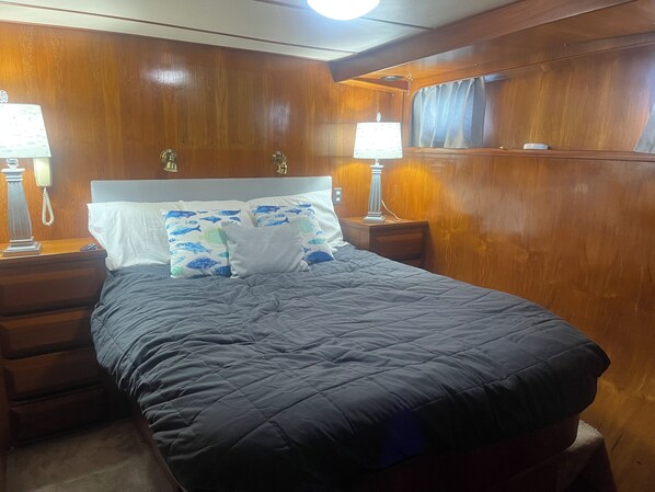 A bed with a quilted grey duvet, two bedside tables with lamps, and a wooden headboard. - TIMEWARP 84 FOOT YACHT CLOSE TO THE BEACH CAN RELOCATE (Madeira Beach)