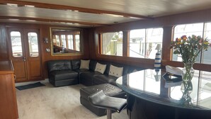 A modern interior with a leather sofa, a round glass table, and a view of the marina through large windows.