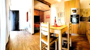 Une cuisine moderne avec des meubles en bois, une table à manger avec des chaises et un mur en briques.