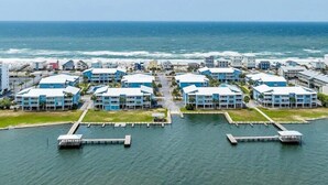A coastal hotel with multiple blue buildings, a marina with docks, and a view of the ocean. - Sea Oats 105h 3 Bedroom Condo (Gulf Shores)